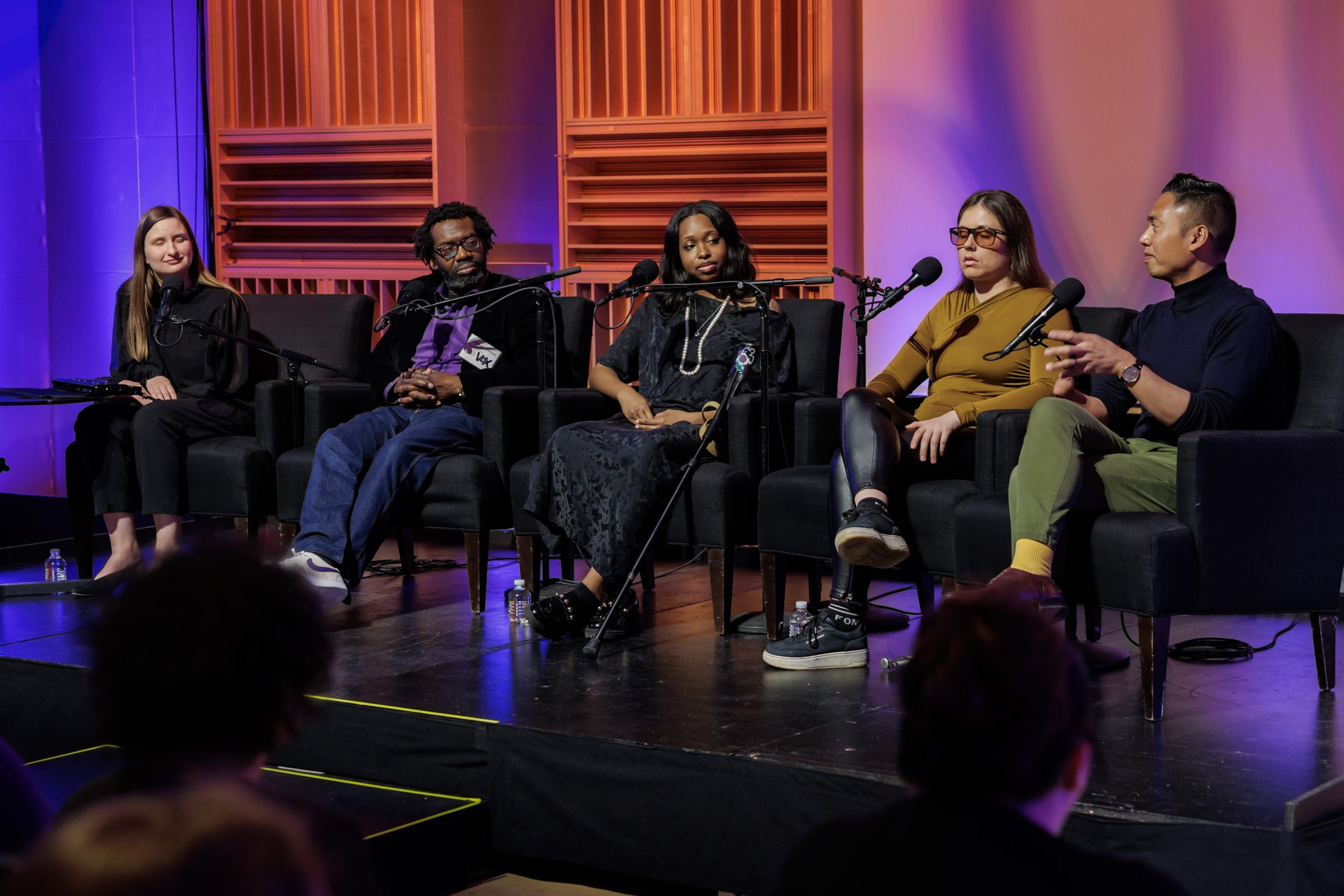 panelists sit in front of microphones during a panel event