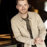 man leans against piano