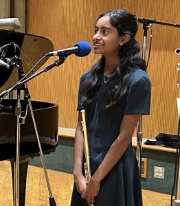 girl at microphone holds flute