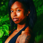 woman looks at camera in front of foliage