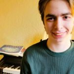 boy smiles in front of piano