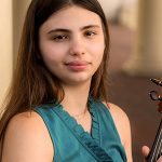 young woman holds viola and looks out